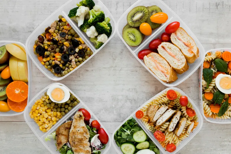 Variedade de marmitas com legumes, frutas, frango e saladas