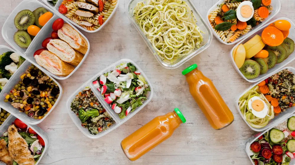 Marmitas balanceadas com macarrão, saladas, frutas e sucos de laranja prontas para entrega